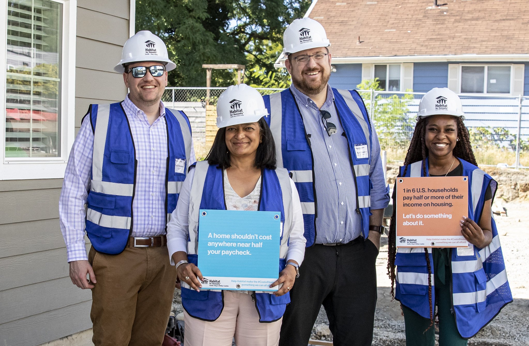 4 Habitat staff, volunteers and legislators wearing Habitat safety helmets